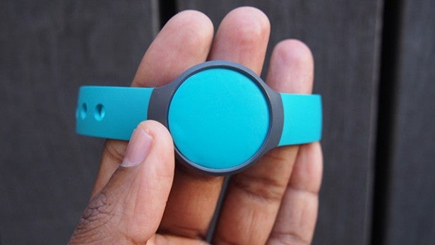 Hand holding a teal Misfit Flash fitness tracker.