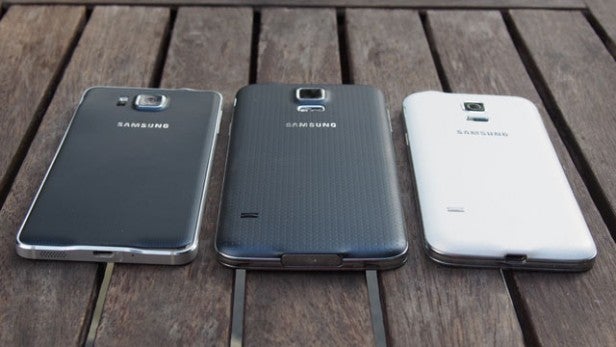 Three Samsung smartphones on a wooden surface.