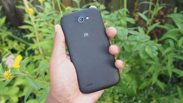 Hand holding a ZTE Blade Q Mini smartphone outdoors.