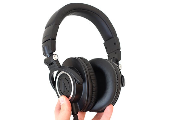 Hand holding Audio-Technica ATH-M50x professional studio headphones.