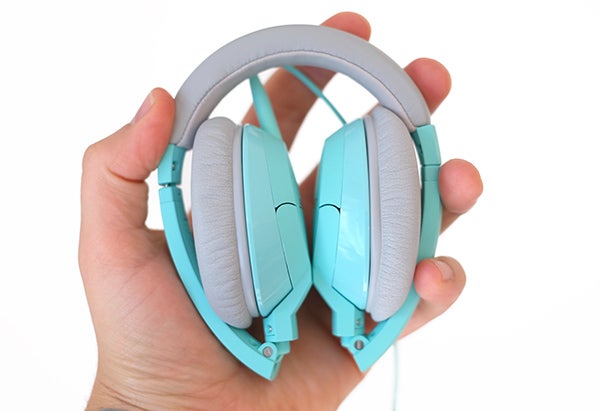 Hand holding folded turquoise Bose SoundTrue On-Ear headphones.