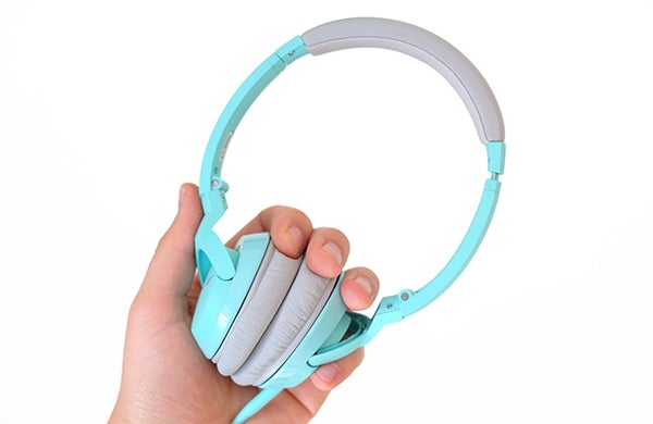 Hand holding turquoise Bose SoundTrue On-ear headphones.