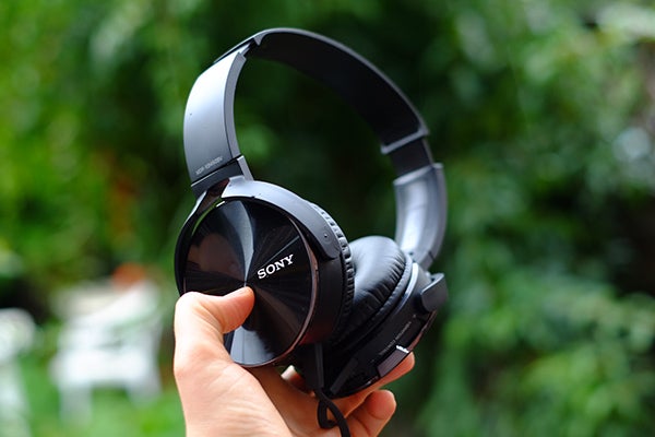 Sony MDR-XB450BV headphones battery compartment with AA batteries.Hand holding a Sony MDR-XB450BV headphone outdoors