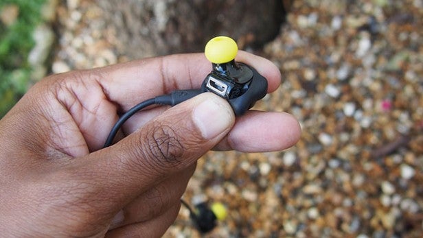 Hand holding Jabra Sport Pulse earbud with USB port visible.