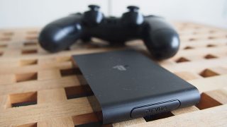PS TV device with controller on wooden surface.