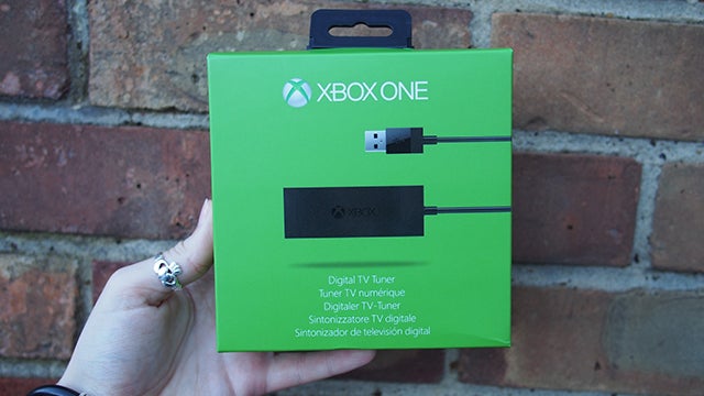 Hand holding Xbox One Digital TV Tuner packaging.