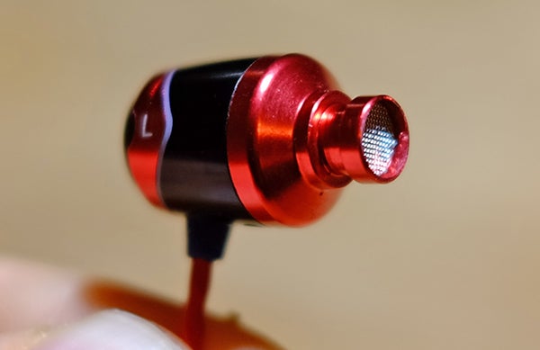 Close-up of SoundMagic E10S in-ear headphone in red and black.