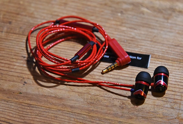 SoundMagic E10S earphones with red cables on a wooden surface.