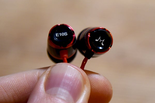 Close-up of SoundMagic E10S in-ear headphones held in hand.