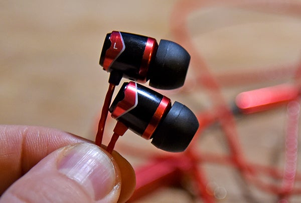 Close-up of SoundMagic E10S earphones held in hand.