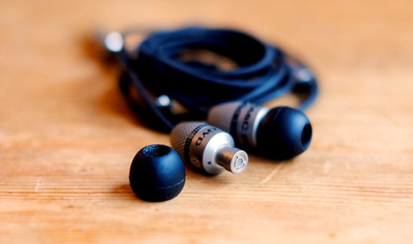 Atomic Floyd SuperDarts Titanium earphones on wooden surface.