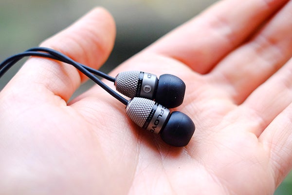 Atomic Floyd SuperDarts Titanium earphones resting on a palm