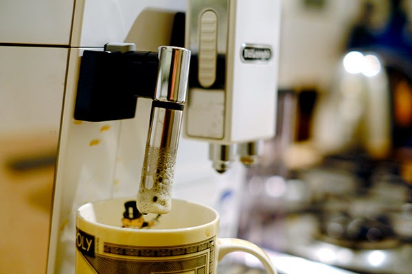 DeLonghi Eletta espresso machine pouring coffee into cup.