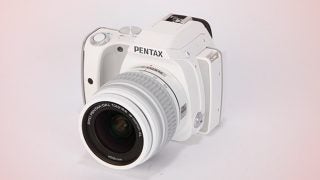 White Pentax K-S1 DSLR camera with lens on a plain background.