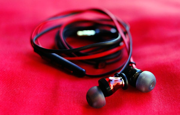 Sennheiser Momentum In-Ear headphones on red background.