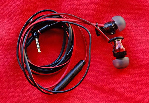 Sennheiser Momentum In-Ear headphones remote control close-up.Sennheiser Momentum In-Ear headphones on red background.Sennheiser Momentum In-Ear earbud on red fabric.