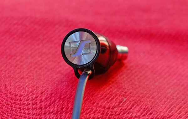 Sennheiser Momentum In-Ear headphones on red background.Sennheiser Momentum In-Ear earbud on red fabric.