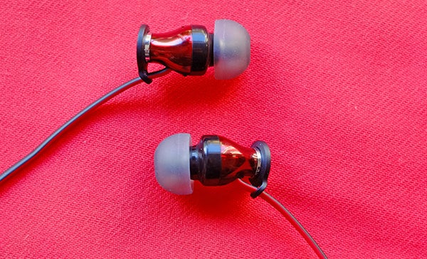 Sennheiser Momentum In-Ear headphones on red background.