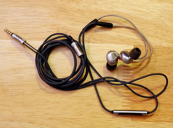 RHA T10i earphones with over-ear hooks on wooden surface.