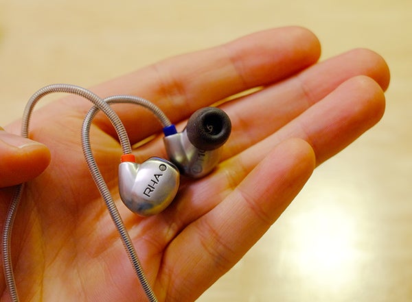 RHA T10i earphones held in a person's palm.