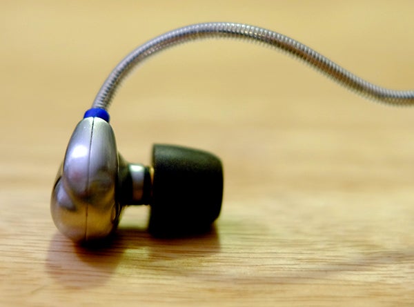 RHA T10i earphone on wooden surface.