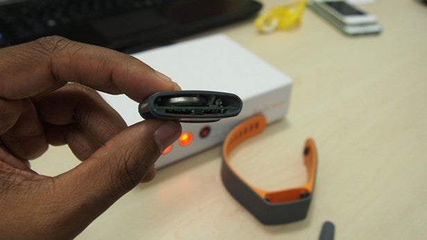 Person holding Acticheck Assure wristband with open charging port.Hand holding Acticheck Assure wristband during setup.