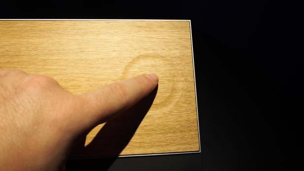 Hand holding BeoSound Moment interface with color wheel.Finger interacting with BeoSound Moment's wooden touch interface.