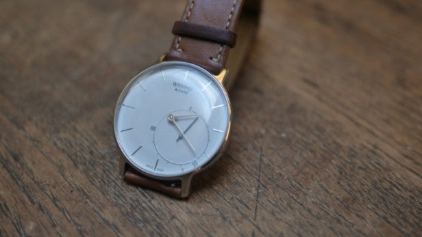 Withings Activité watch with brown leather strap on wooden surface.Withings Activité watch on a wrist with leather strap.Close-up of Withings Activité watch strap with Close-up of Withings Activité watch on wooden surface.