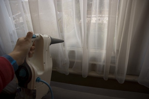 Person using Vax Steam Fresh Combi on curtains.