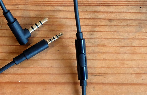 Close-up of AKG Y50 headphone jack and inline remote on wooden surface.
