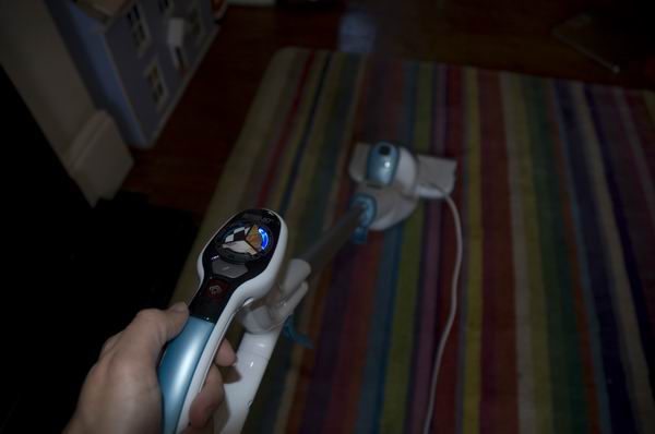 Hand holding Black & Decker Steam-Mop in home setting.