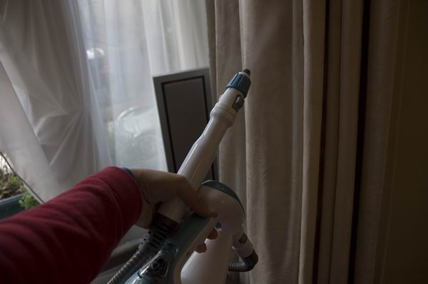Person using Black & Decker steam mop near curtains.