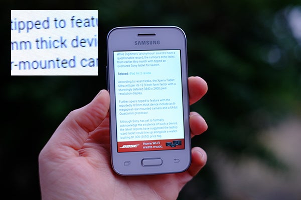 Hand holding a Samsung Galaxy Young 2 displaying an article.