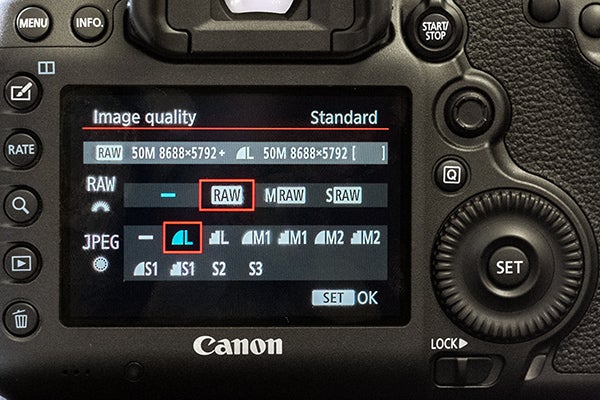 Close-up of Canon EOS 5DS camera settings screenCanon EOS 5DS DSLR camera with red-ringed lens held in hand.