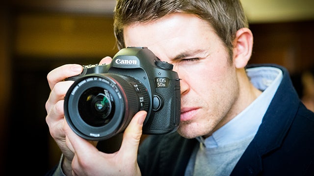 Man taking a photo with a Canon EOS 5DS camera.