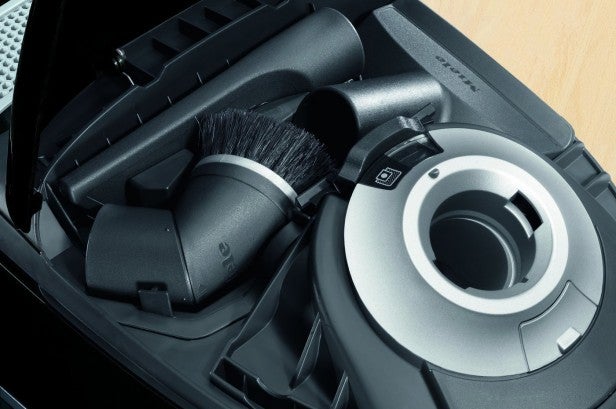 Close-up of Miele vacuum accessories and storage compartment.