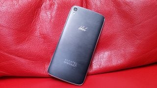 Alcatel OneTouch Idol 3 smartphone on red leather surface.