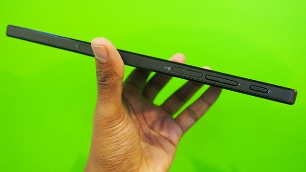 Hand holding Blackphone+ side profile against green background.