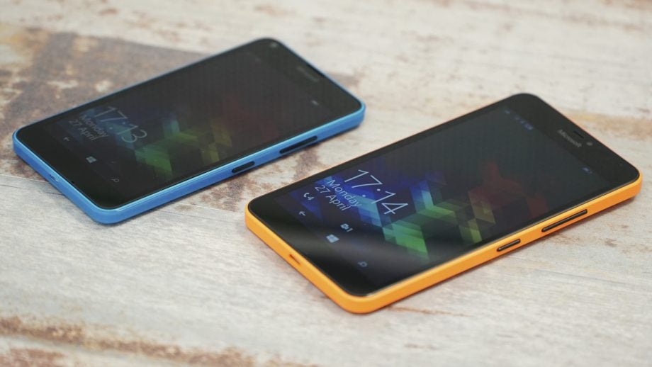 Two Microsoft Lumia 640 smartphones on a wooden surface.