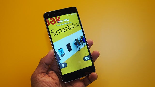 Hand holding a KODAK IM5 Smartphone against a yellow background.