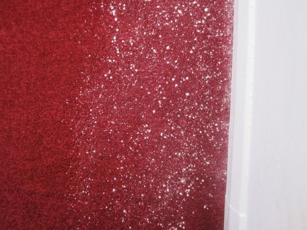 Red carpet with white powder before vacuuming test.