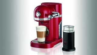 KitchenAid Nespresso Artisan in red with coffee cup and milk frother.