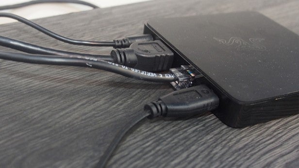 Razer Forge TV box connected with multiple cables on wood surface.Razer Forge TV box connected to power and HDMI cables.