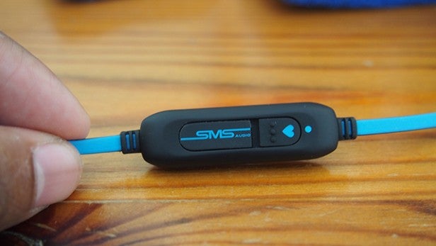 SMS Audio BioSport earphones with in-line control on wooden table.