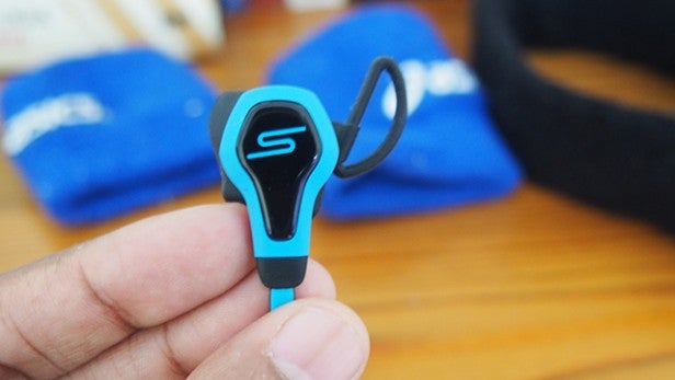 Hand holding SMS Audio BioSport earbud with blue accents