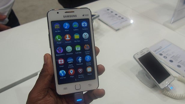Hand holding a Samsung Z1 smartphone displaying apps.