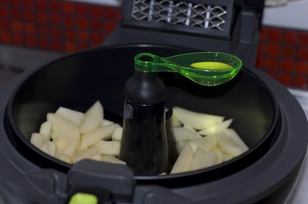 Tefal ActiFry Express with raw potato slices and measuring spoon.