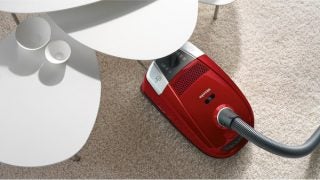 Miele Compact C2 vacuum cleaner on a carpeted floor.