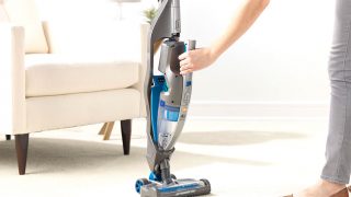 Person using Vax Air Cordless Vacuum in a living room.