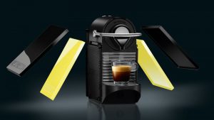 Magimix Nespresso Pixie machine with espresso shot and capsules.